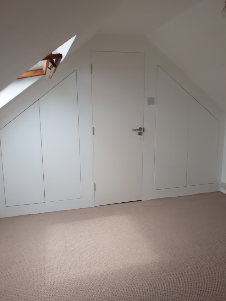 White fitted wardrobes built into a sloped loft bedroom wall by MyDeskin Carpentry, Keynsham